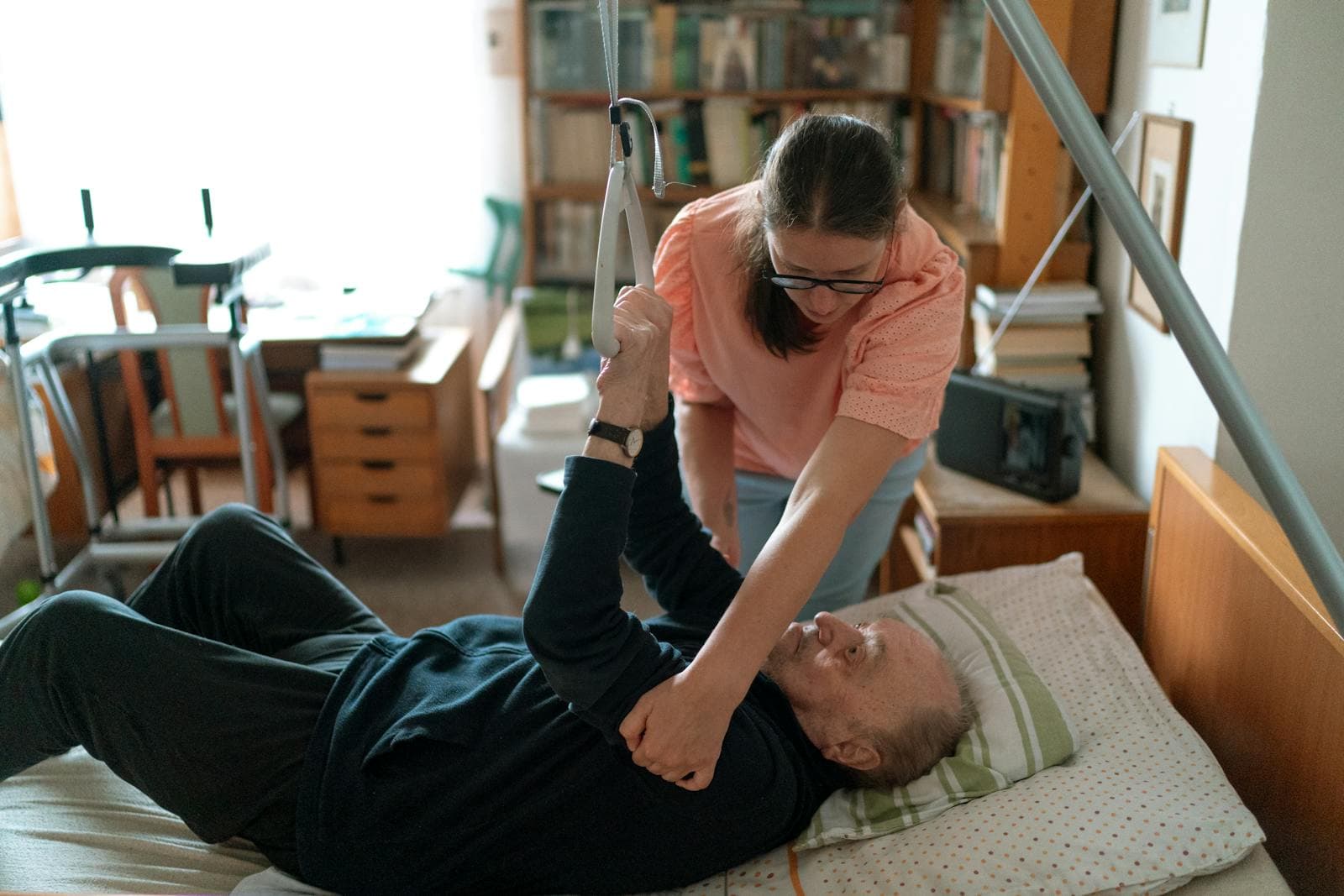 A companion caregiver helps an elderly man in his living room with day-to-day routines.